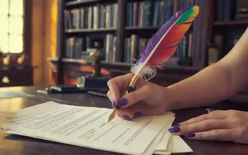 A hand signs paperwork with a Feather Quill Fountain Pen